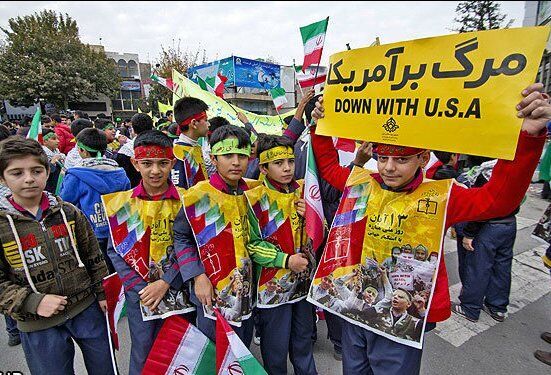 Student protesters hold "Down with U.S.A." flags to celebrate the anniversary of the Hostage Crisis.