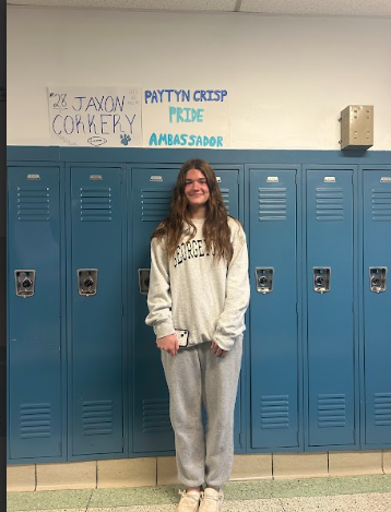 Paytyn standing beside her PRIDE Ambassador poster by her locker.