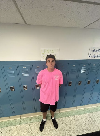 Lennon standing beside his PRIDE Ambassador poster by his locker.