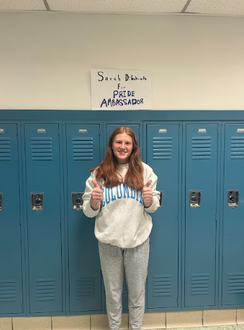 Sarah gives a thumbs up beside her locker.