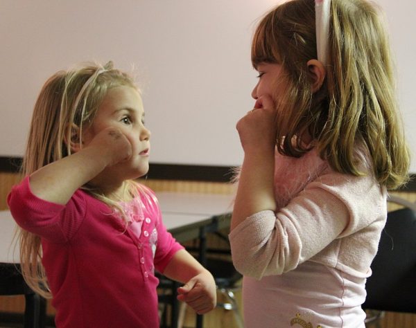 Two girls learning sign language.